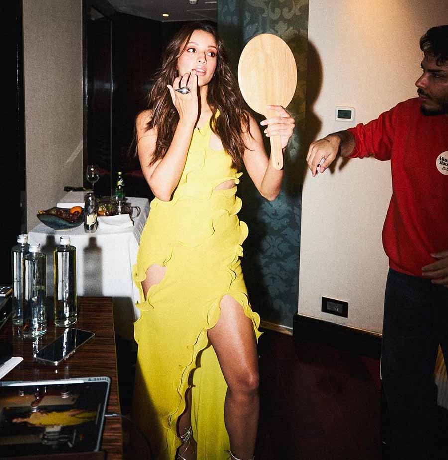 Clad in a yellow slit dress with an asymmetric hemline cascading down in waves, Triptii exuded runway model vibes as she looked into a mirror to touch up her glow.  