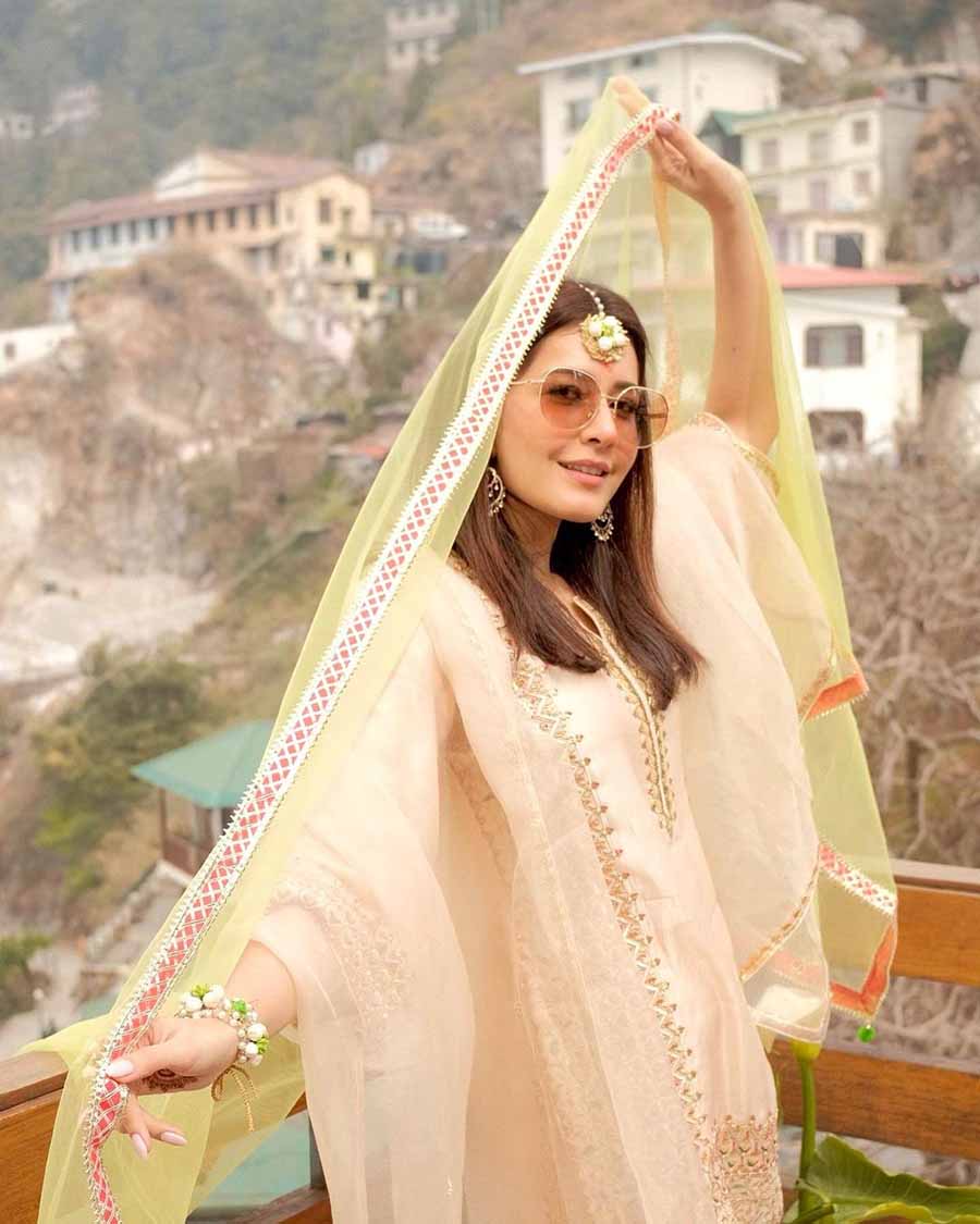 For the haldi ceremony held on Tuesday, Raashii went for a dewy look in a pastel peach garara adorned with gold embroidery at the helm and placket. Floral jewellery and pink-tinted sunglasses completed her look.