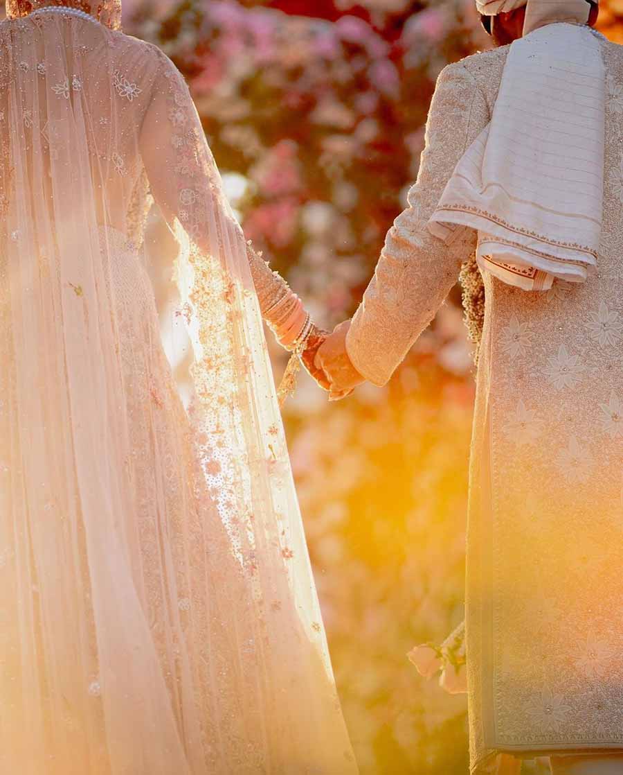 The bride and the groom held hands as they walked down the aisle with flowers forming a fascinating foreground.  