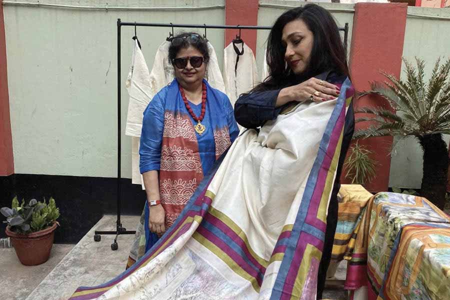 Rituparna Sengupta tries a sari hand-painted by Shampa Mukherji at an exhibition 