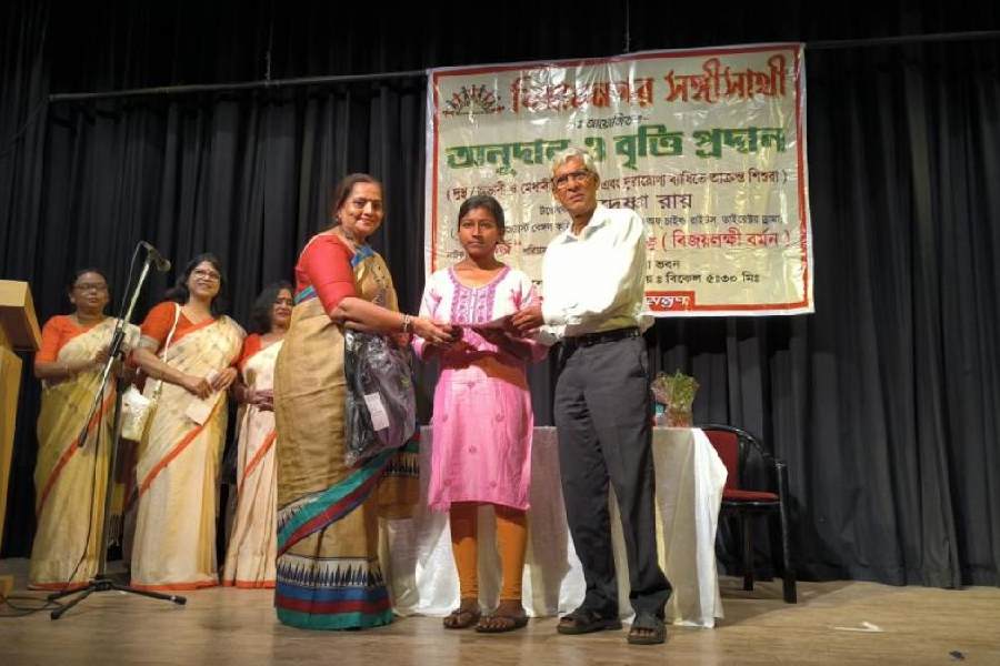 A meritorious girl being handed aid by Sangi Sathi
