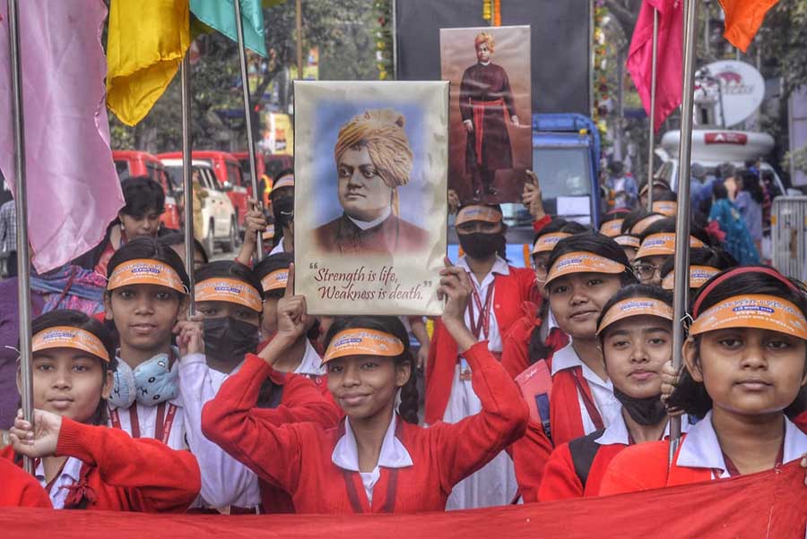 Schoolgirls hold aloft placards with images of Swamiji and colourful flags 