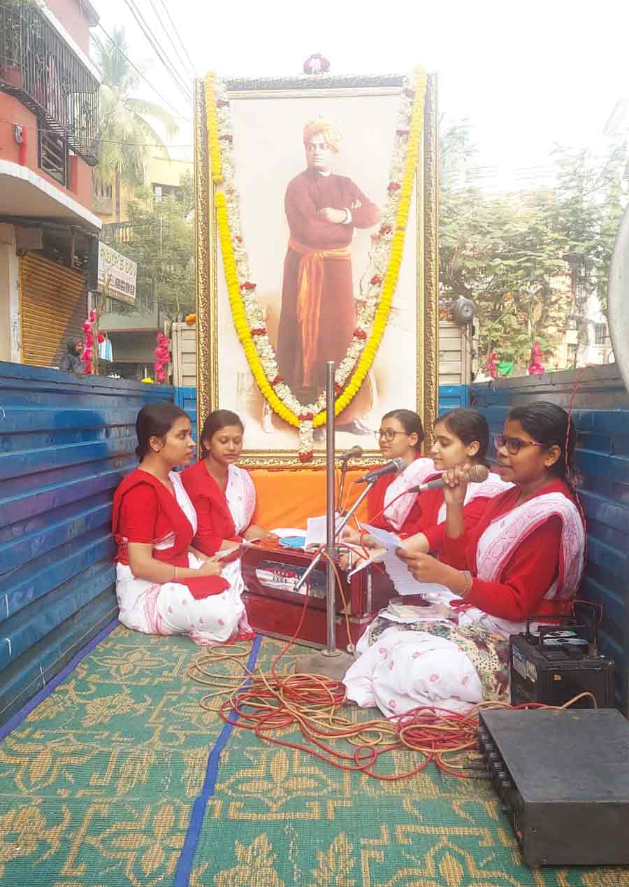 A choir of students of Ramakrishna Sarada Mission Vivekananda Vidyabhavan perform on a mini truck during a procession in Dum Dum