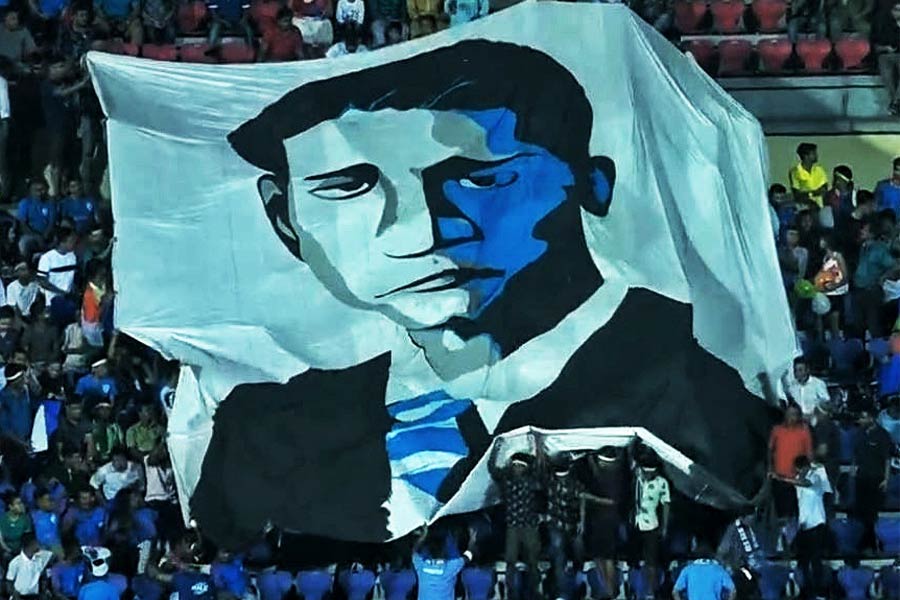 The Blue Pilgrims — as supporters of India’s national football team call themselves — hold up a banner with Talimeren Ao’s face in artwork at the 2020 qualifying match against Qatar in Guwahati