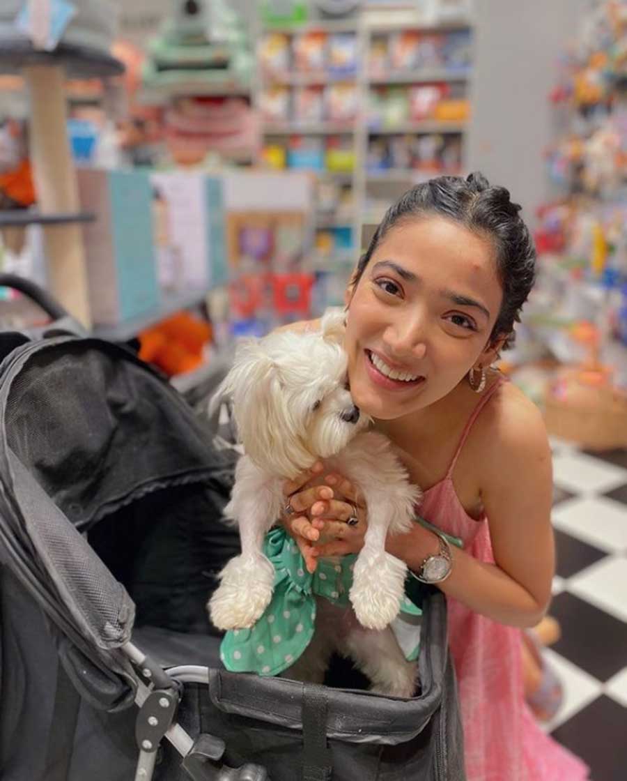 Medha cuddles up her pet dog. The braided hair with the strappy pink dress is a win.