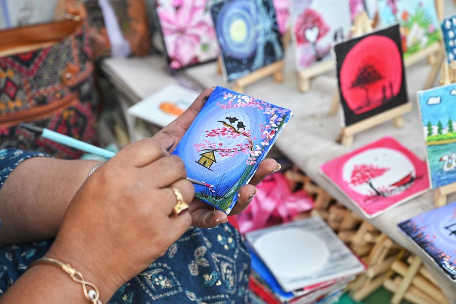 Many artists participate in the Book Fair to sell their artworks and handicrafts. In picture, an artist paints on a mini canvas