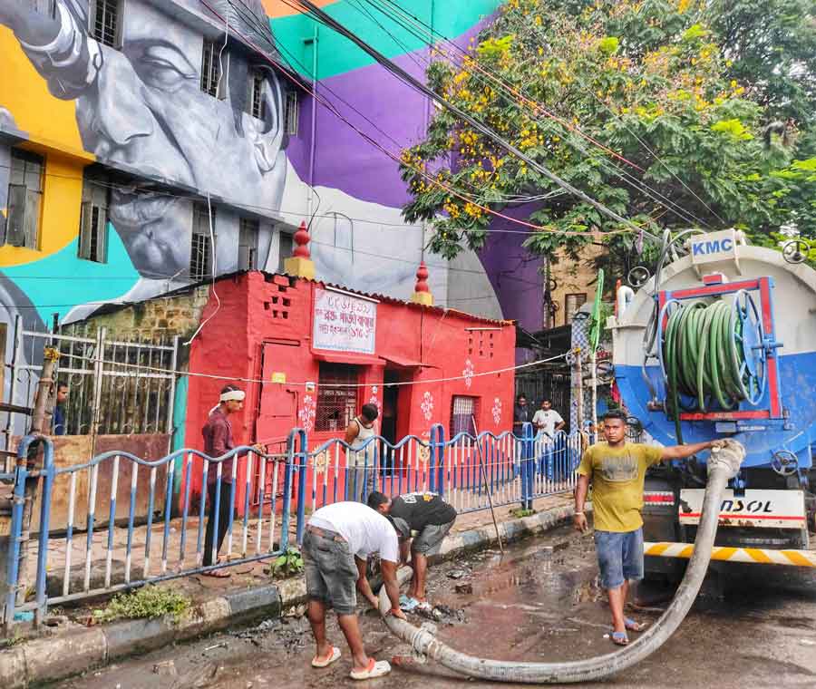 Workers of the sewerage and waste management department of Kolkata Municipal Corporation at work at Deshapran Sashmal Road with a gully pit cleaning machine  