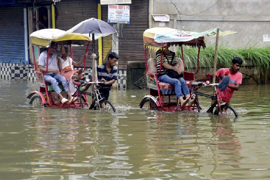 Rickshaw pullers wade through a flooded street after rainfall, in Guwahati, Saturday, July 6, 2024