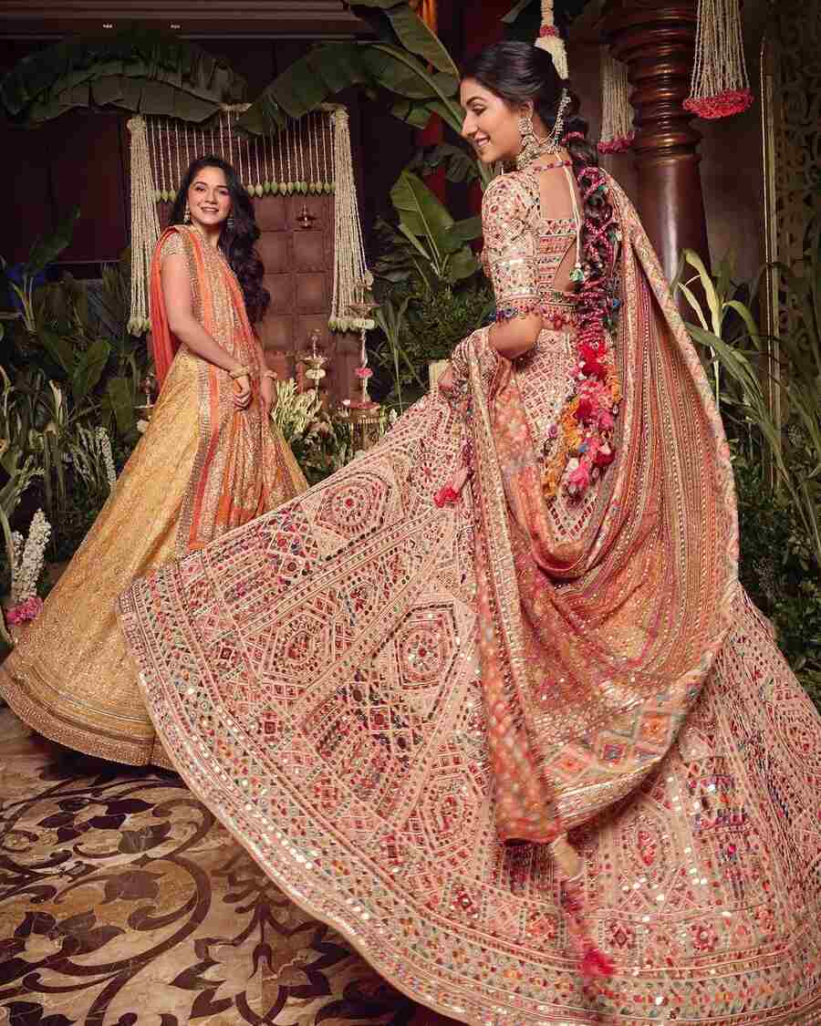 The bride twirled in a peach lehenga choli embellished with multicoloured glass beads. She exuded elegance in a dramatic bubble braid adorned with gajras.
