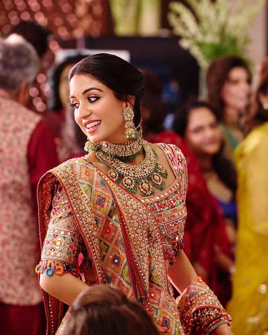 A double-layered kundan necklace with green gems was the highlight of Radhika’s ensemble at one of the ceremonies. She looked radiant in a multicoloured lehenga with geometric motifs. Kohl-rimmed eyes, coral lip shade and tinted cheeks complemented her look.