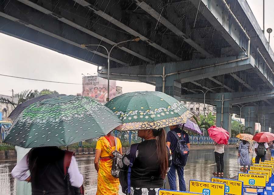 Office-time commuters wait for buses in rain at VIP Road College More on Friday morning