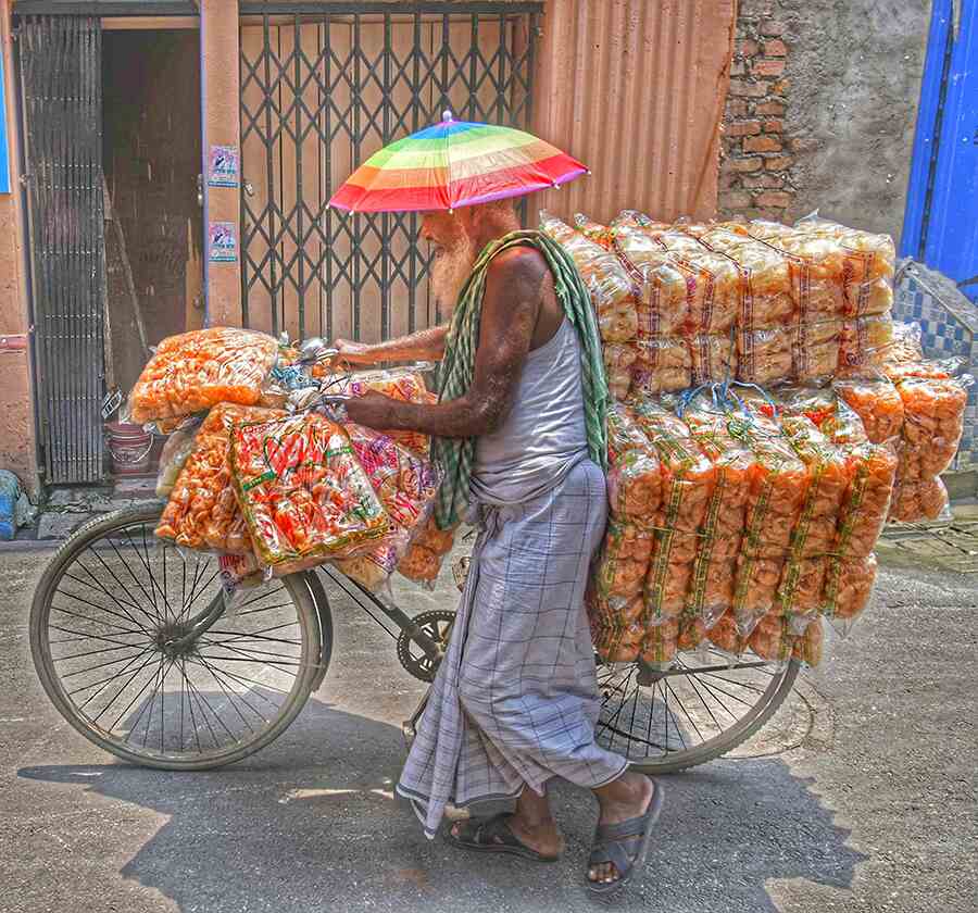 A papad wholeseller sports a colourful hat to shield against the sun while on the way to supply neighbourhood shops in central Kolkata