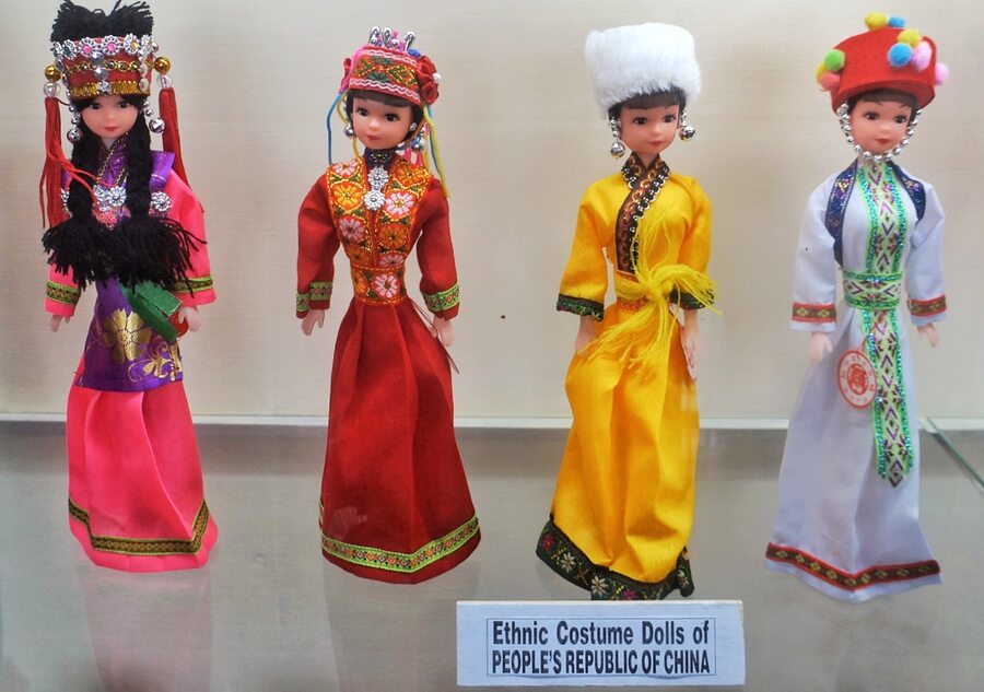 A collection of dolls from China showcases the attire of various groups and regions within the country. Each doll is dressed in traditional attire, complete with headdresses and jewellery which are unique to their region, featuring distinctive styles, patterns, and colours