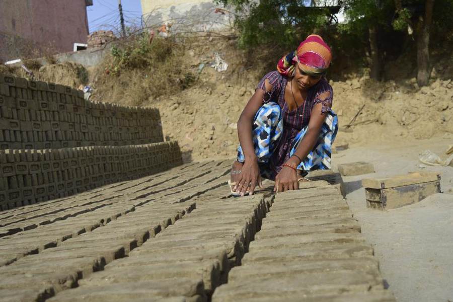 Kanchan Devi bakes bricks outdoors with cloth wrapped around her head to protect her