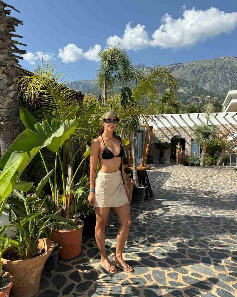 Black wayfarers, a beige baseball cap and matching flip flops complemented Triptii’s daytime outfit for the beach.  