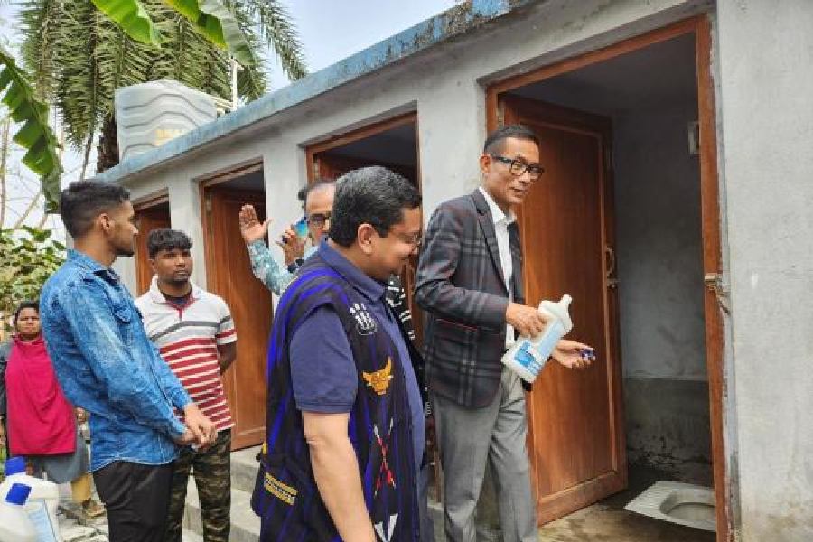 Watinuksung Jamir (right) approaches a cabin in a community toilet complex in Duttabad with Rajesh Chirimar next to him