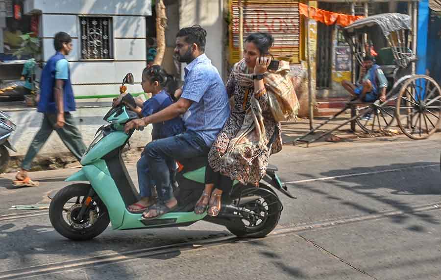 A helmetless family rides down Chitpore Road on their two-wheeler