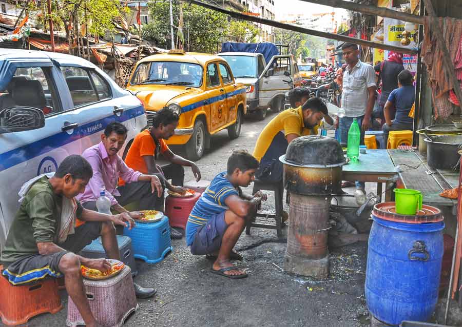 People relish lunch at a pice hotel on a pavement at Chitpur Road on Friday