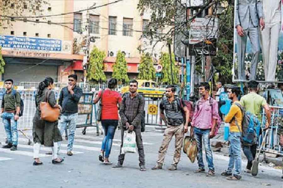 Commuters wait for a bus at Park Street-Jawaharlal Nehru Road crossing on Sunday afternoon