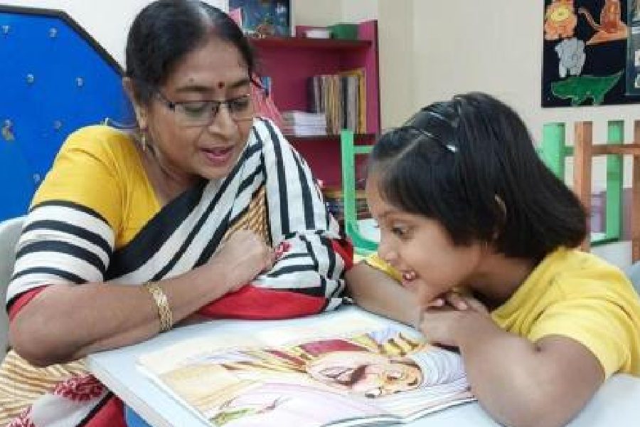 A guardian reads with a student at Indus Valley World School