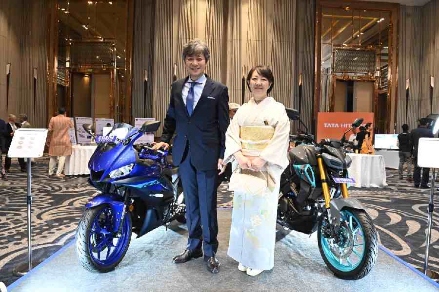 The hosts, Japan consul general Koichi,  Nakagawa and his wife Yayoi, pose in front of Yamaha Racing bikes on display 