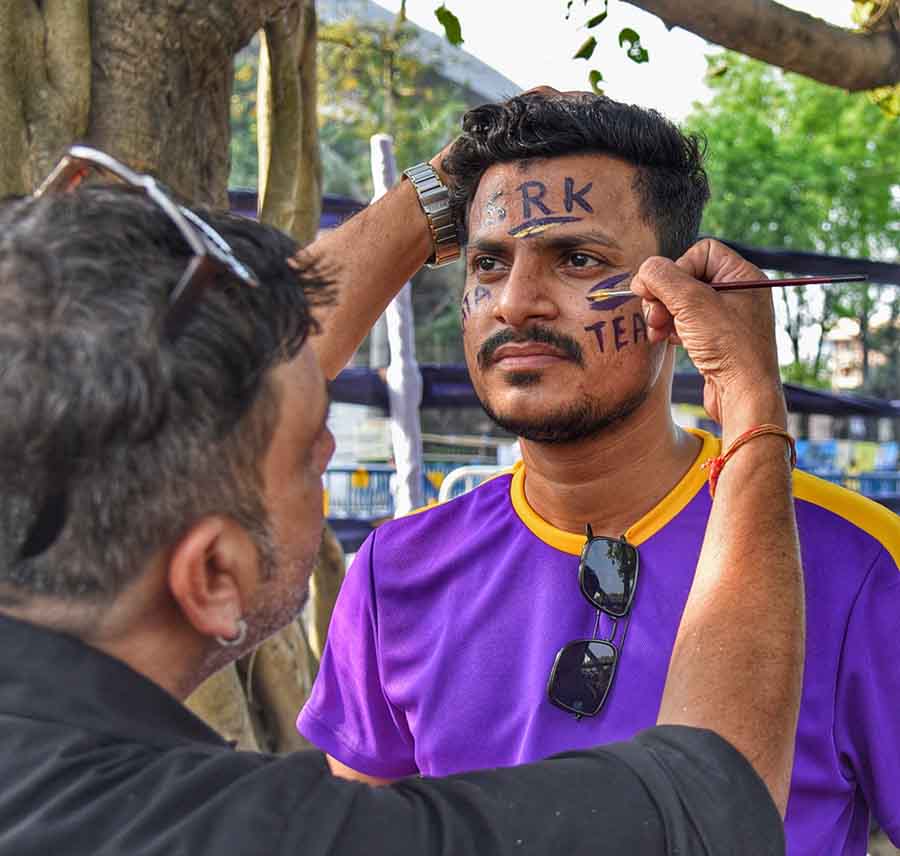 A purple jersey-clad KKR fan puts aside his sunglasses to get his face painted near the Eden Gardens 