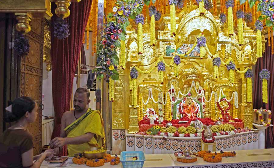 A devotee receives prasad from the priest at Siddhivinayak Temple. Siddhivinayak Temple on Muktaram Babu Street is decorated with flowers and fruits are being offered on the occasion of Dol purnima and Holi   