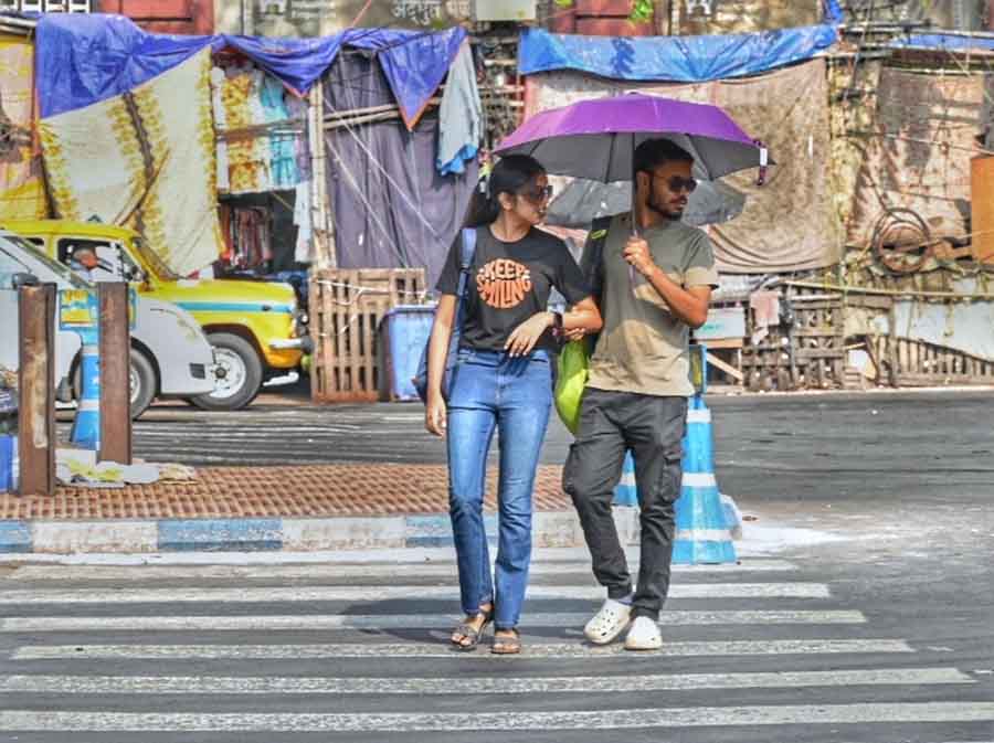 A couple, armed with an umbrella, brave the afternoon sun on Wednesday