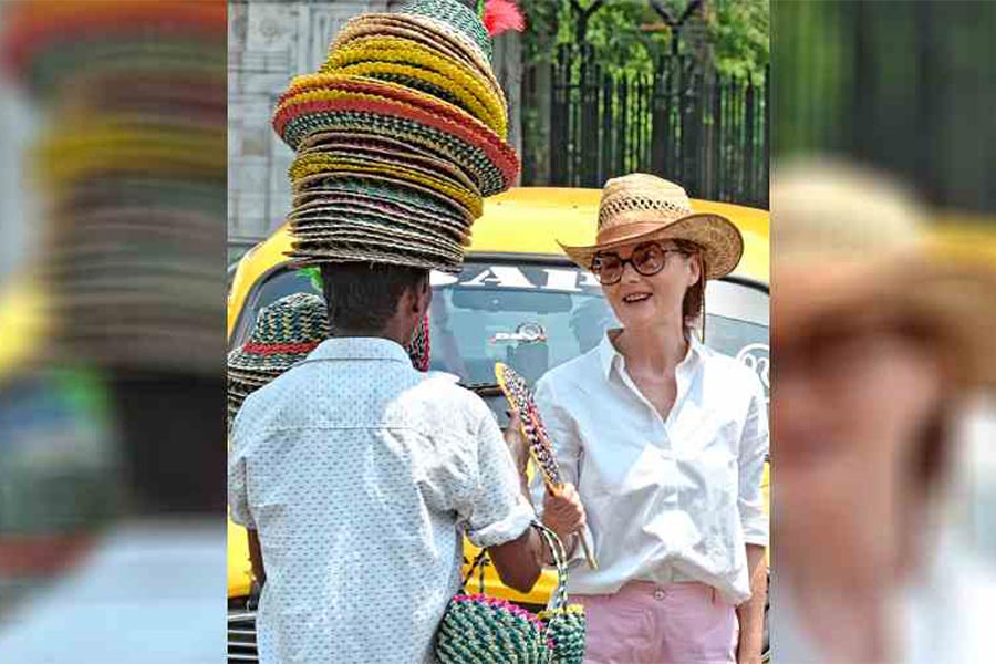 A tourist buys a hand fan in front of the Victoria Memorial  