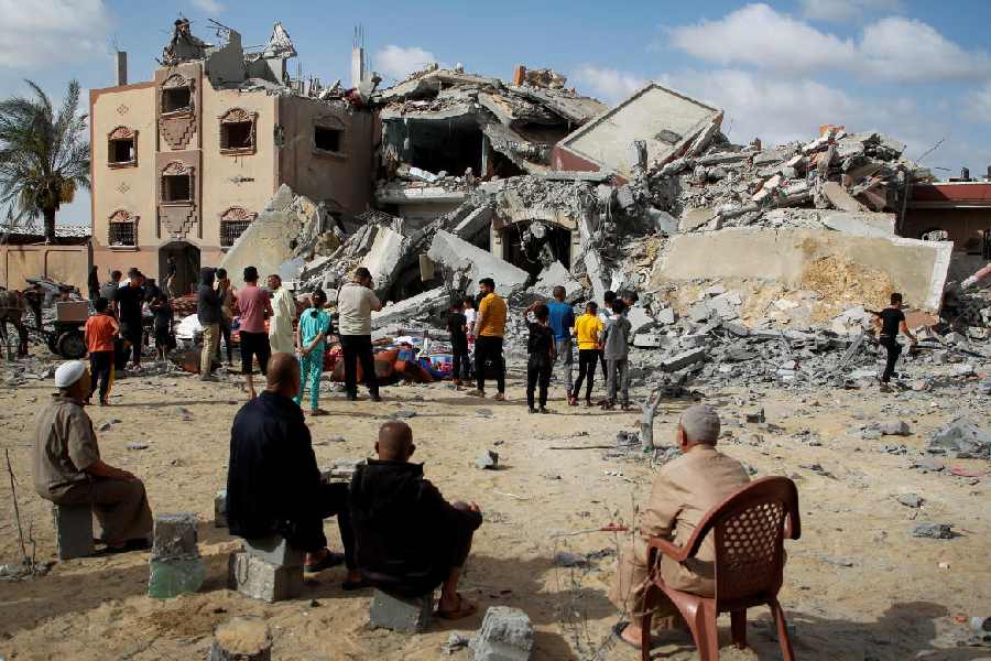 Palestinians look at the site of an Israeli strike on a house, amid the ongoing conflict between Israel and Hamas, in Rafah