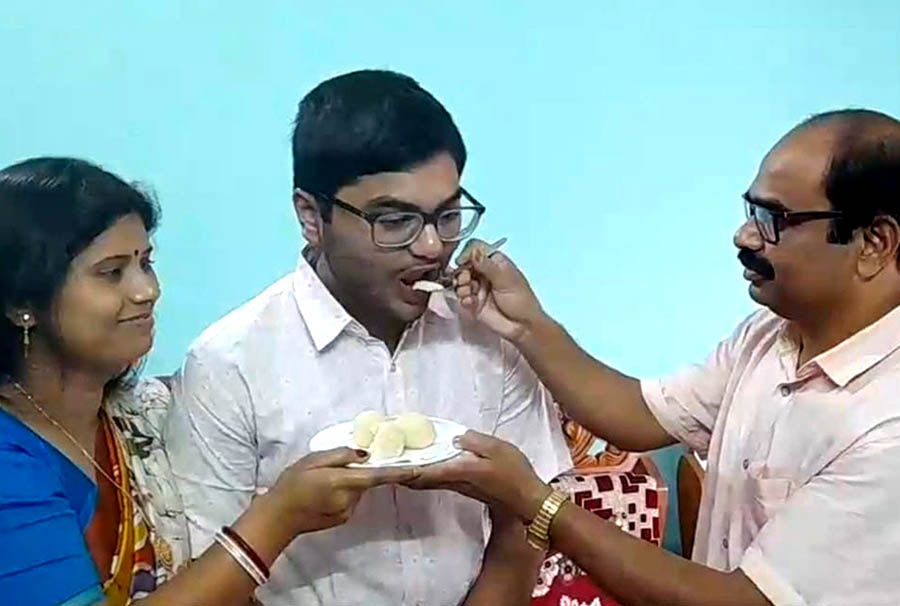Ecstatic parents of Aveek Das, who stood first in the Higher Secondary Examination, treat him to sweets at their family residence in Alipurduar on Wednesday 