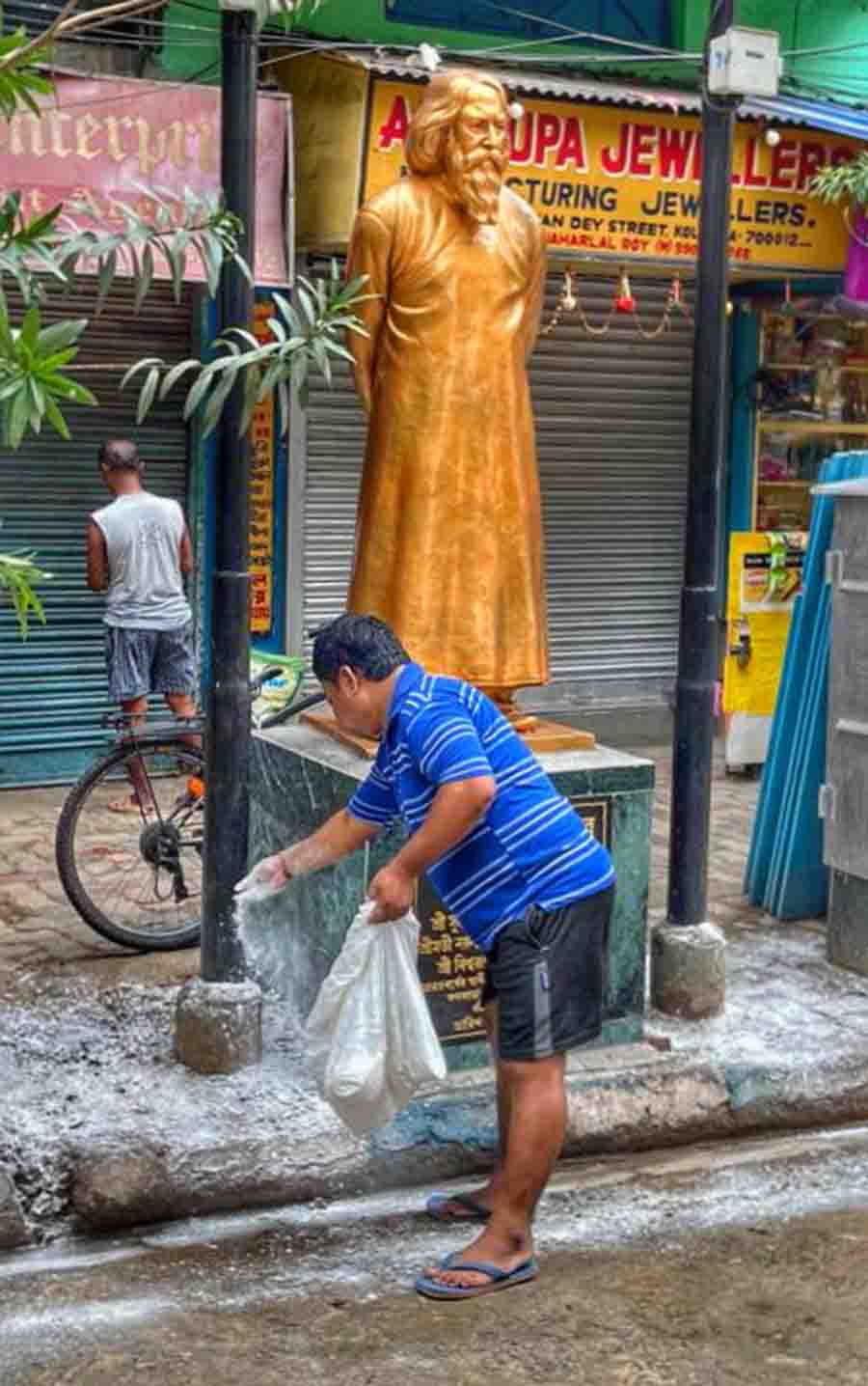 A Kolkata Municipal Corporation employee spreads bleaching powder at Sashi Bhushan Dey Street near Lebutola Park on Wednesday