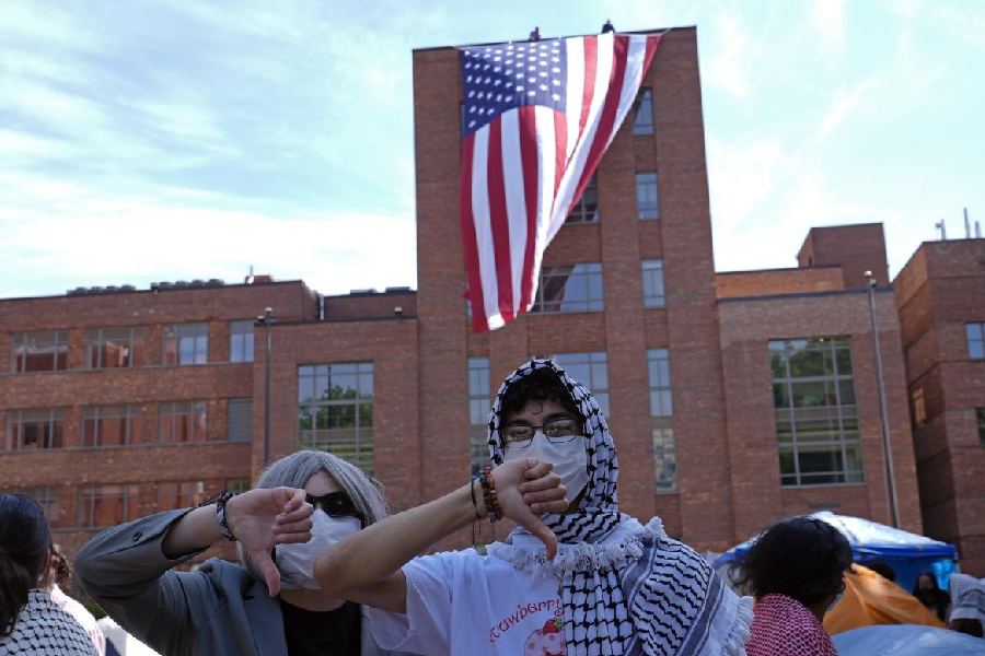 Protesters react as a giant American flag is unfurled on Lisner Hall on the campus of George Washington University in Washington, Friday, May 3, 2024, as demonstrators protest the Israel-Hamas war