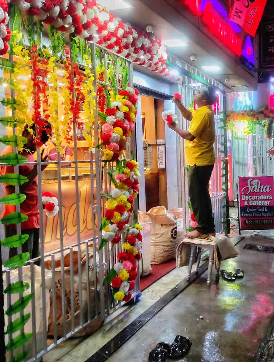 A shopkeeper in Keshtopur decorates his jewellery shop with artificial flowers on the eve of Akshay Tritiya