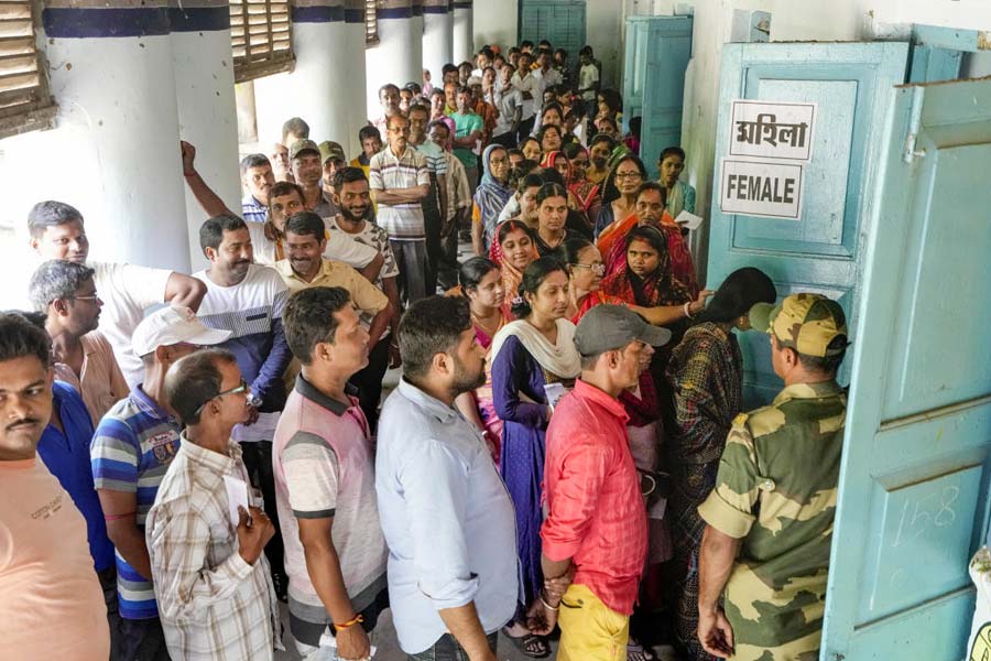Voters wait in a queue at a polling station to cast their votes for the fourth phase of Lok Sabha elections, in Bardhaman, Monday, May 13, 2024.