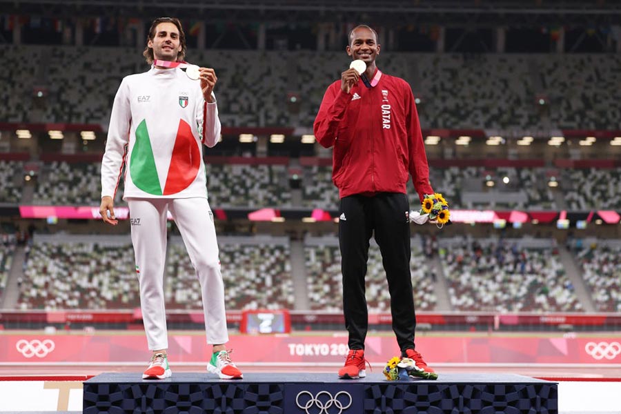 Joint gold medalists Mutaz Essa Barshim of Team Qatar and Gianmarco Tamberi of Team Italy celebrate on the podium during the medal ceremony for the Men's High Jump at the Olympic Stadium in Tokyo, 2021