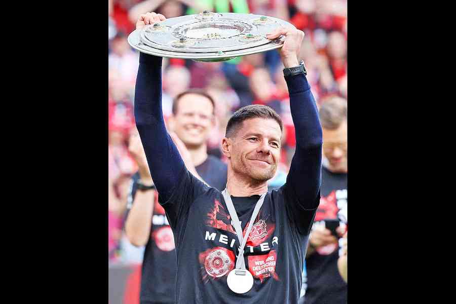 Bayer Leverkusen coach Xabi Alonso celebrates with the trophy after winning the Bundesliga and going unbeaten