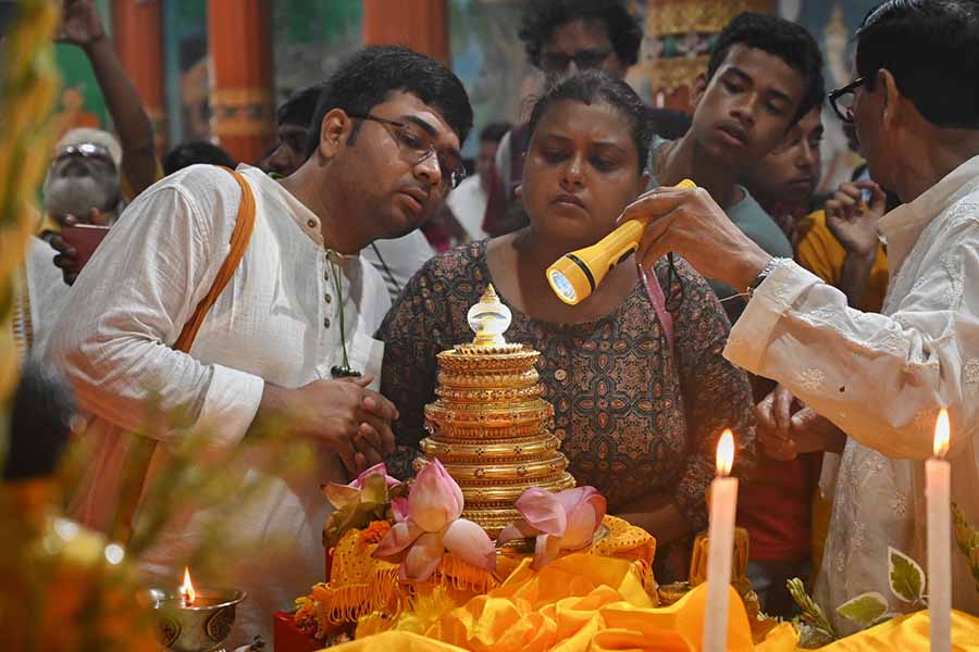 A monk shows devotees a relic of Lord Buddha with torchlight at the Mahabodhi Society