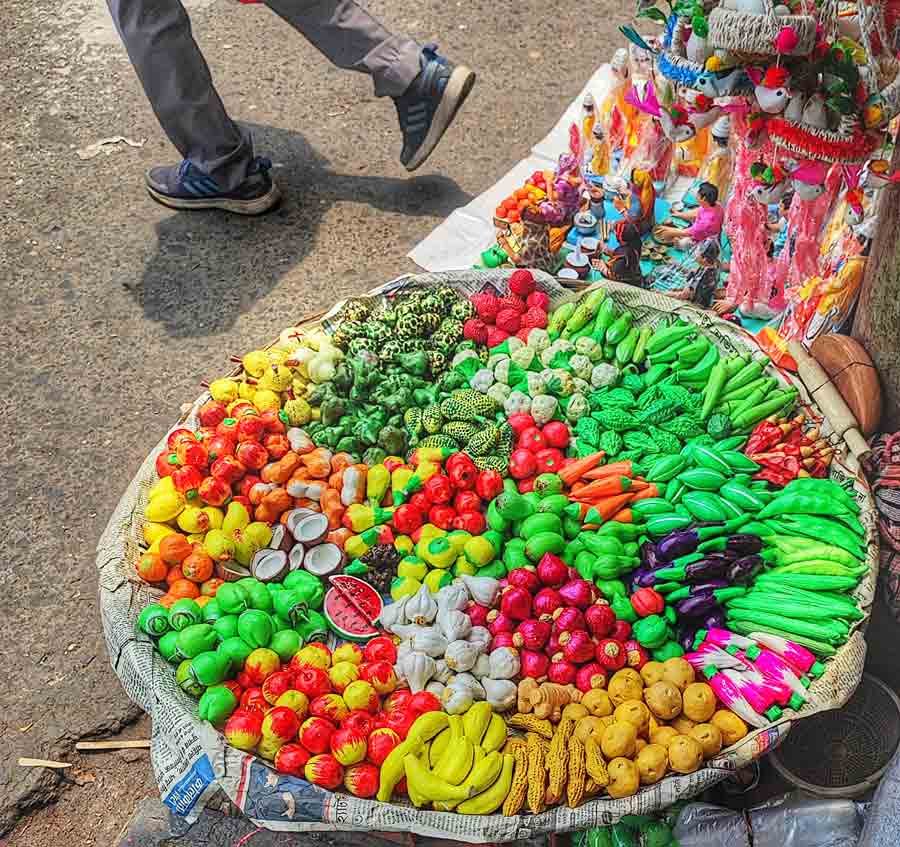 A vendor selling vegetables and dolls made of clay on the footpath at Gariahat crossing  