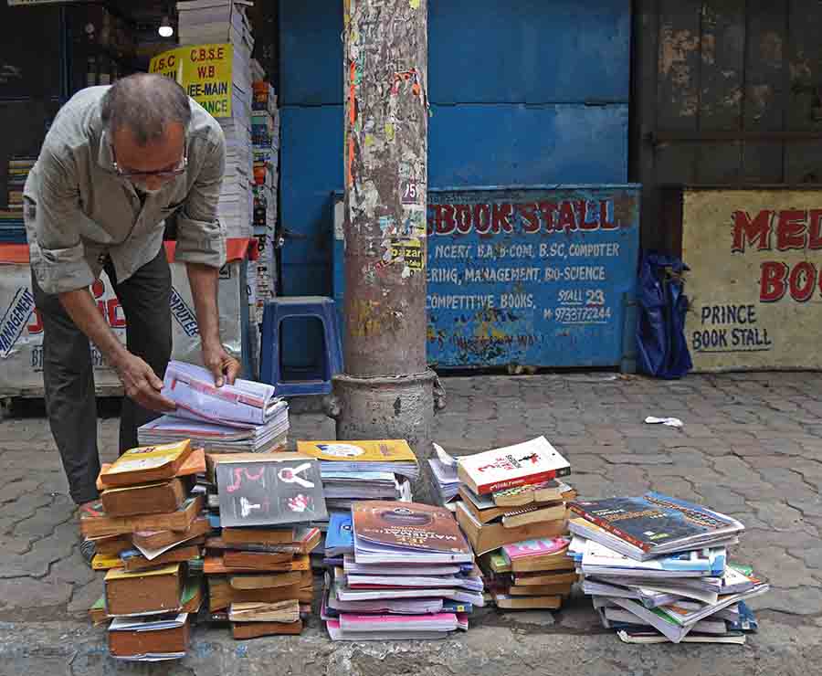The owner of a books stall at the College Street ‘Boipara’ spreads books under the sun for drying on Tuesday. The entire stretch was waterlogged since Sunday night owing to incessant rainfall triggered by the cyclone 