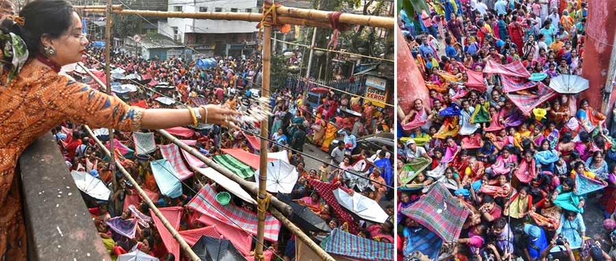 Women distribute ‘prasad’ of Annakut Puja to devotees waiting on the road below at Madan Mohantola on Saturday