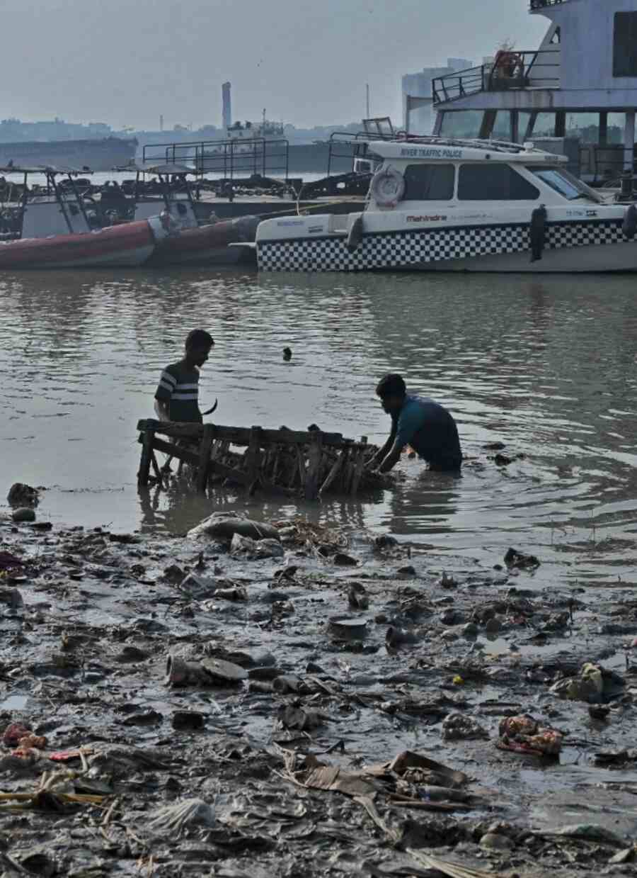 Kolkata Municipal Corporation workers retrieve debris of immersed idols from the Hooghly at Baje Kadamtala ghat on Tuesday