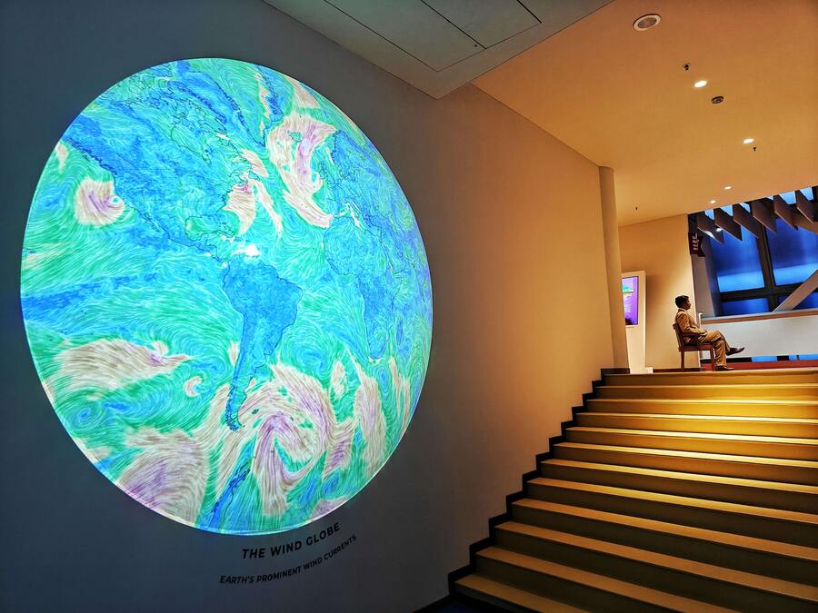 The climate change timeline is displayed on a wall, while an electronic globe maps the rising temperatures over the years of each region that the user wants to track. Six tunnels have inverted U-shaped LCD screens that show causes of the climate crisis through spectacular sights of glacial melting, wildfires and oil spills