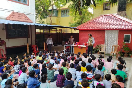 Children at Rammohan Mission School, in coloured dress on Celebration of Children's Day , watching a Grand Magic Show. Children are mesmerized by a captivating magic show, their faces filled with wonder as the magician performs mind-boggling tricks. Laughter and gasps of amazement fill the air as coins disappear, colorful scarves float, and impossible illusions unfold. The magic sparks joy and excitement, leaving everyone in awe