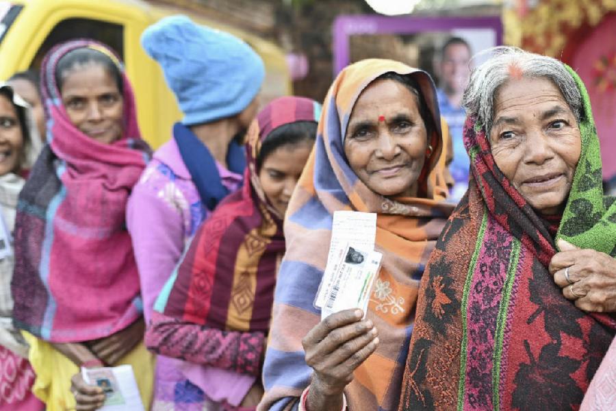 A voter shows her identification card as she waits to cast her vote, with others, at a polling booth during the second and last phase of Jharkhand Assembly elections.