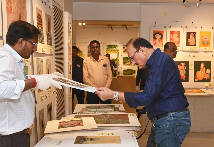 A visitor pores over several artworks