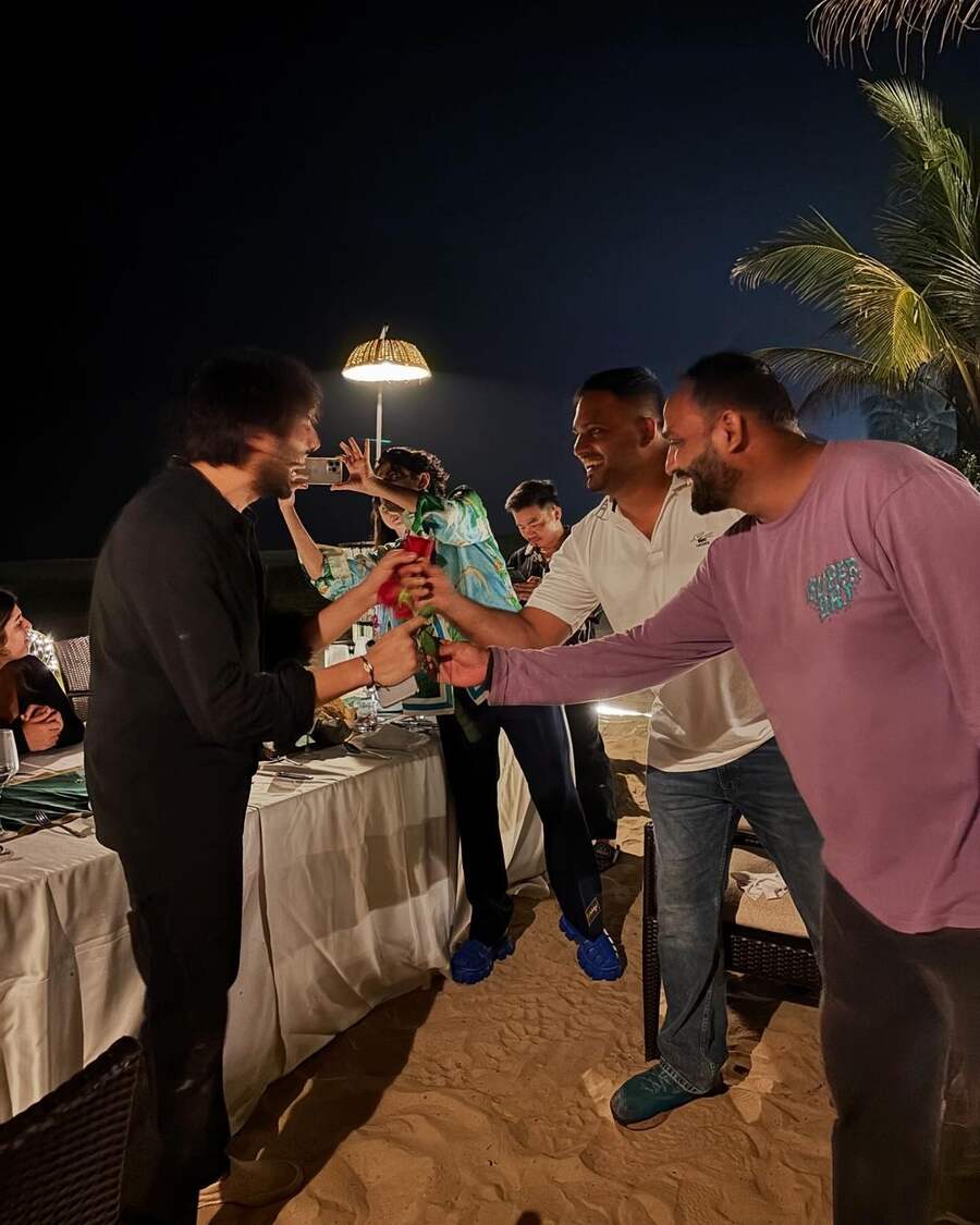 Kartik burst out laughing as his friends handed him roses during an event held on the beach at night.