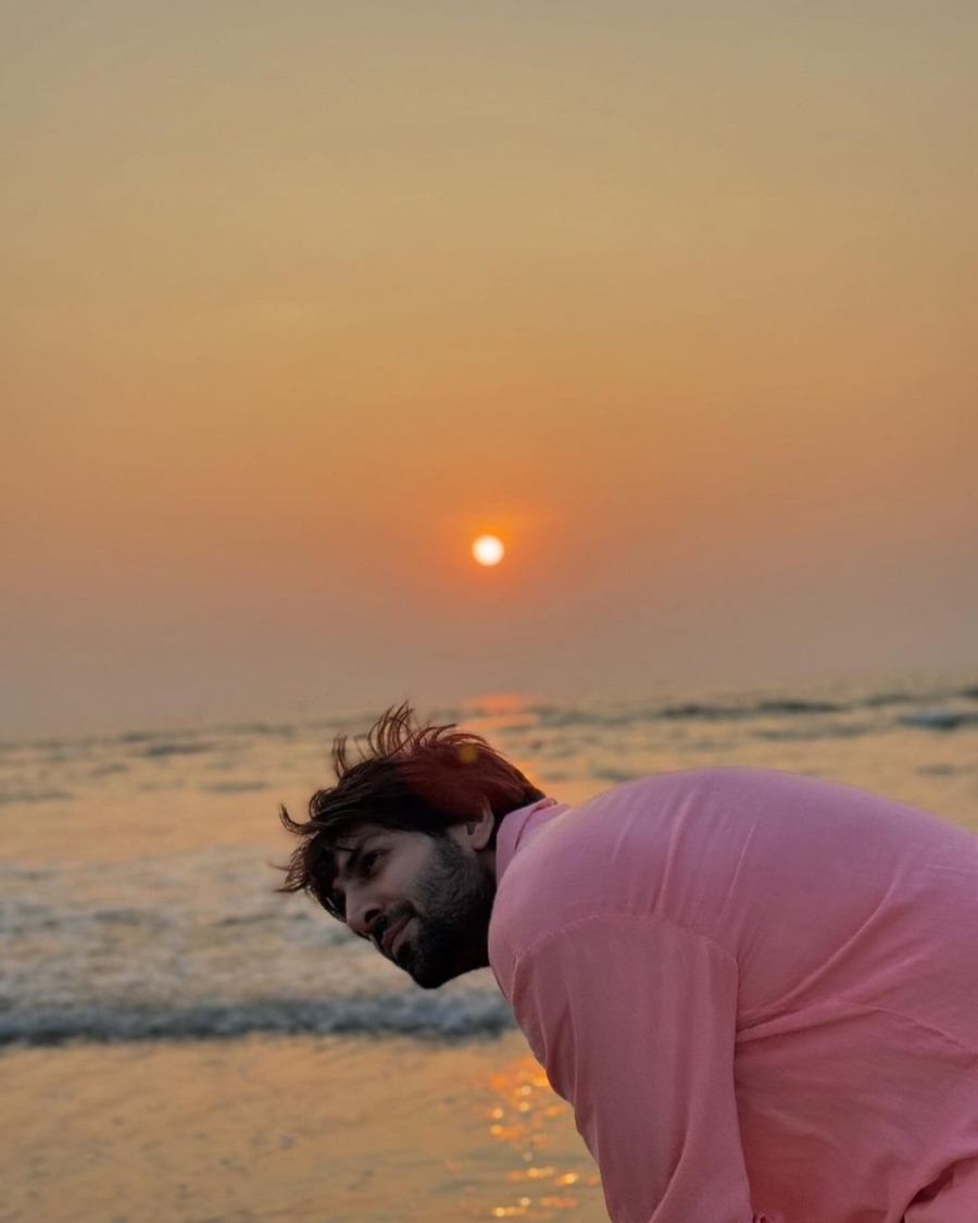 In a candid moment, Kartik stood by the beach at sunset and felt the waves wash his feet. 
