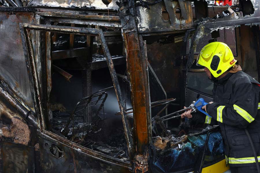 Firefighter works to extinguish a burning bus on the outskirts of Bangkok.