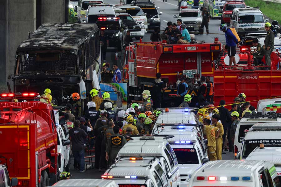 Rescue workers extinguish a burning bus carrying teachers and students from Wat Khao Phraya school.